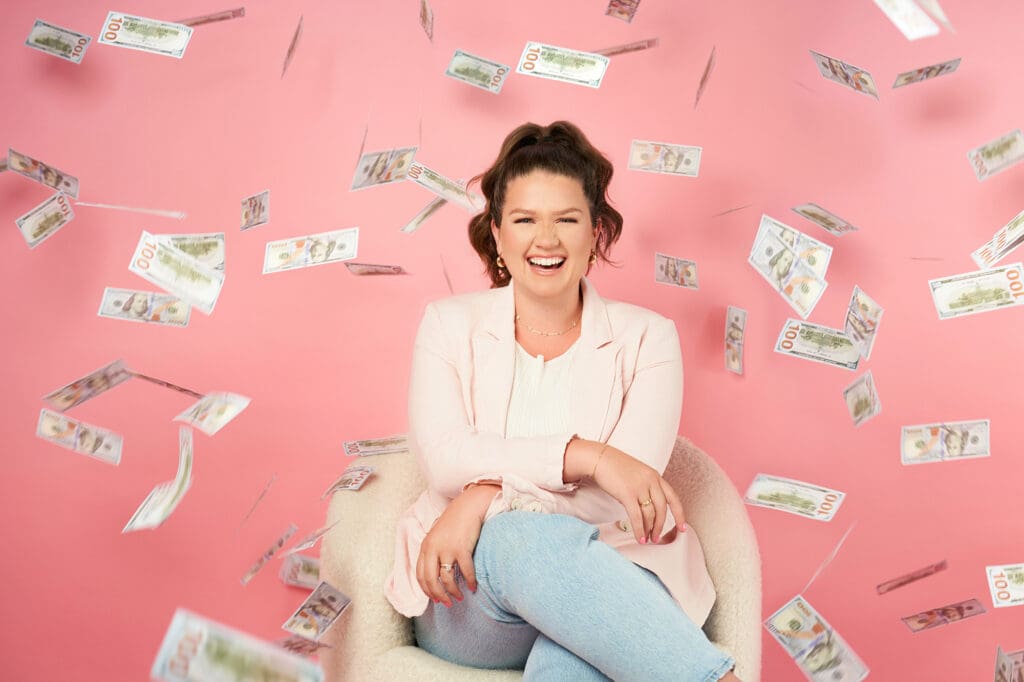 business coach taylor lee on pink background with money flying all around her
