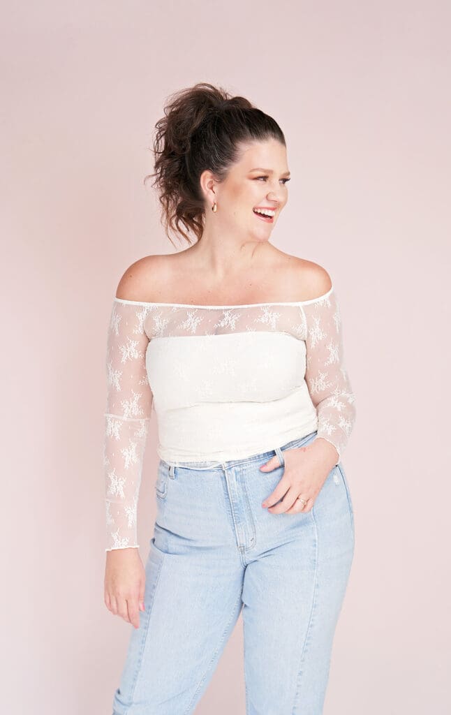 business coach taylor lee brand photo for course fully booked on repeat soft pink background with her in white lace top and light blue jeans