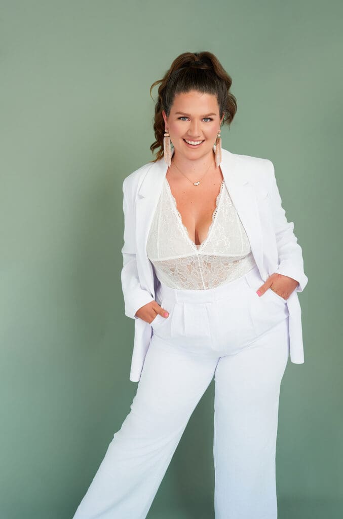 business coach taylor lee brand photo for her mastermind sage green background with her in white suit and lace underneath