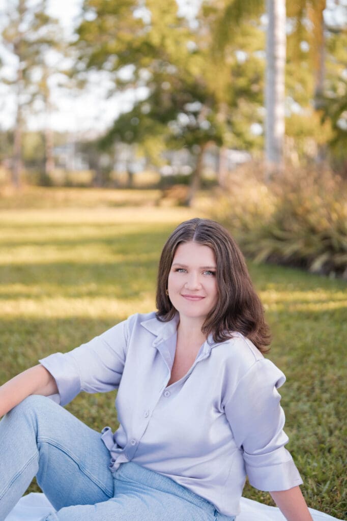 taylor lee CEO coach branding photos in lavender satin top sitting on a blanket in the grass