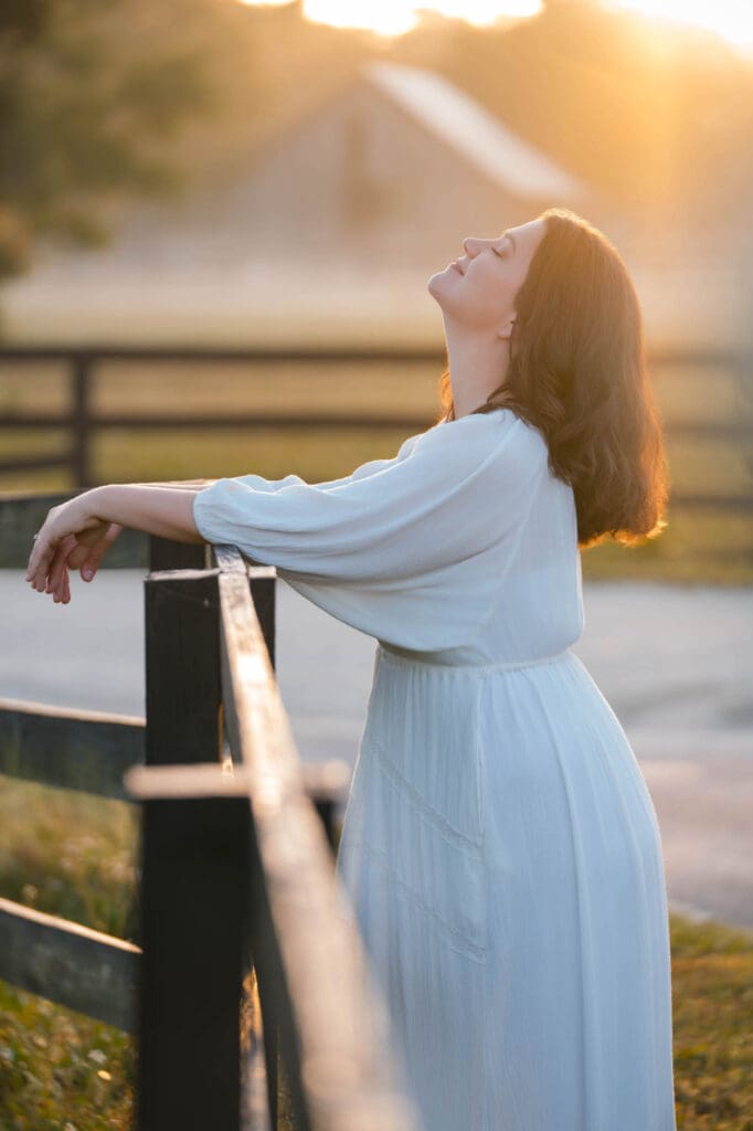 female entrepreneur business coach taylor lee at sunrise at her farm in white dress