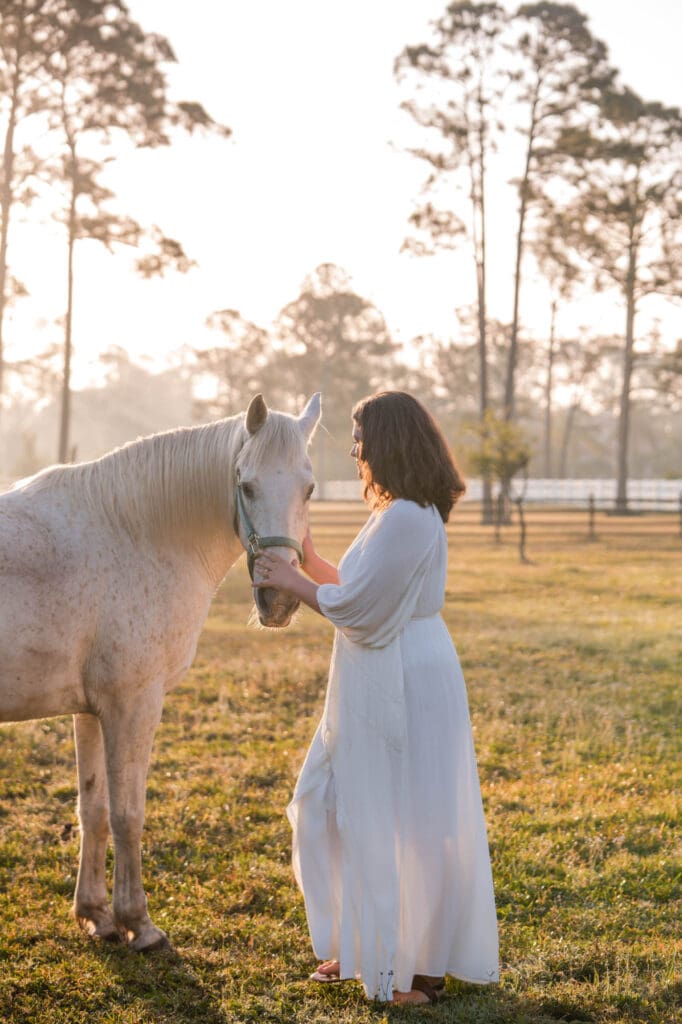 mindset coach taylor lee with her horse on her farm near St. Augustine, Floria in a white dress
