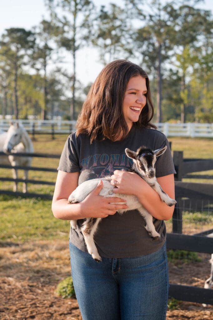 life and business coach taylor lee holding a baby goat on her farm in Florida