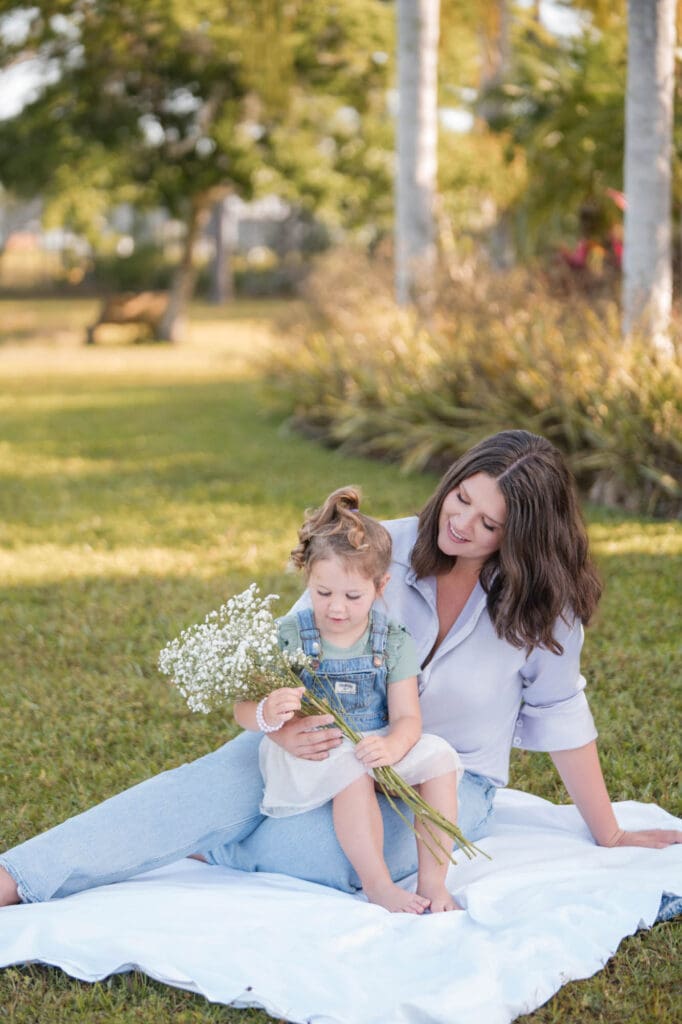 personal brand photos for high ticket coach taylor lee sitting on a blanket in the grass with her daughter