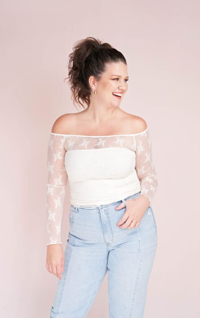 premium business coach taylor lee in white lace top and blue jeans on light pink background