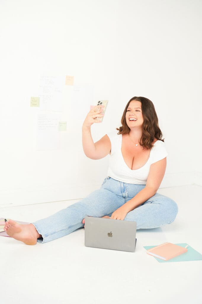 high level CEO branding session taylor lee talking on phone to client sitting on floor in white top and jeans with sticky notes behind her
