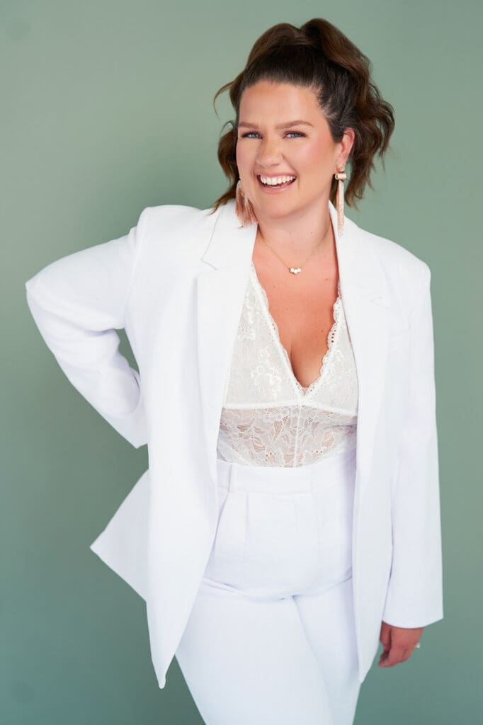 photoshoot for online coaching business with business coach taylor lee in white lace suit on sage green paper backdrop